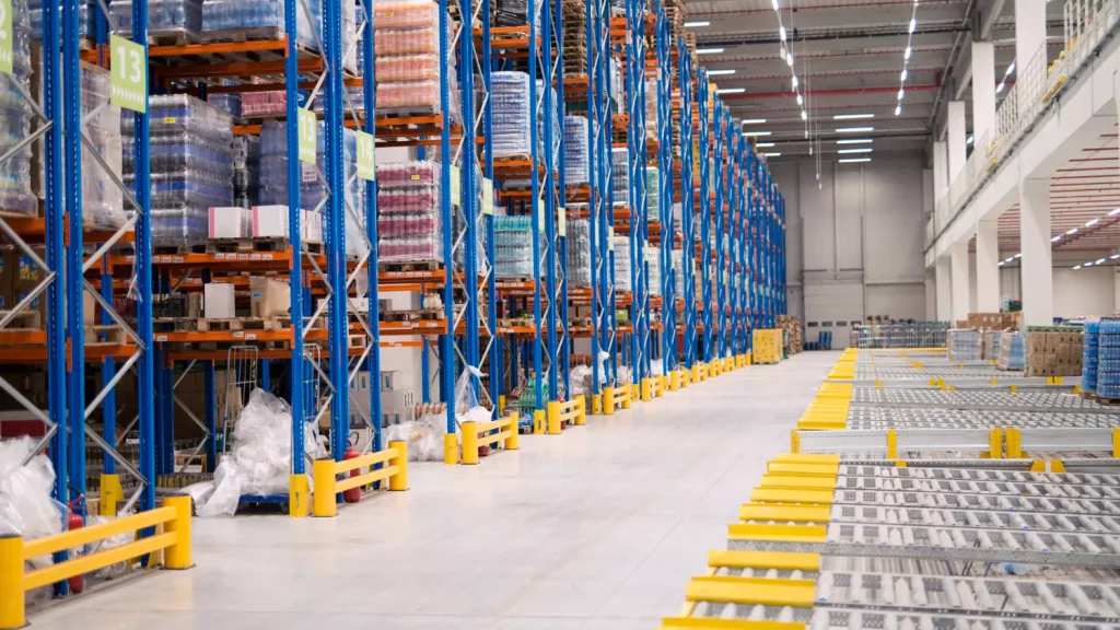 Egy modern logisztikai központ belső tere magasraktári állványrendszerekkel és automatizált szállítópályákkal, bemutatva az intralogisztika kiállításokon felvonultatott technológiákat.